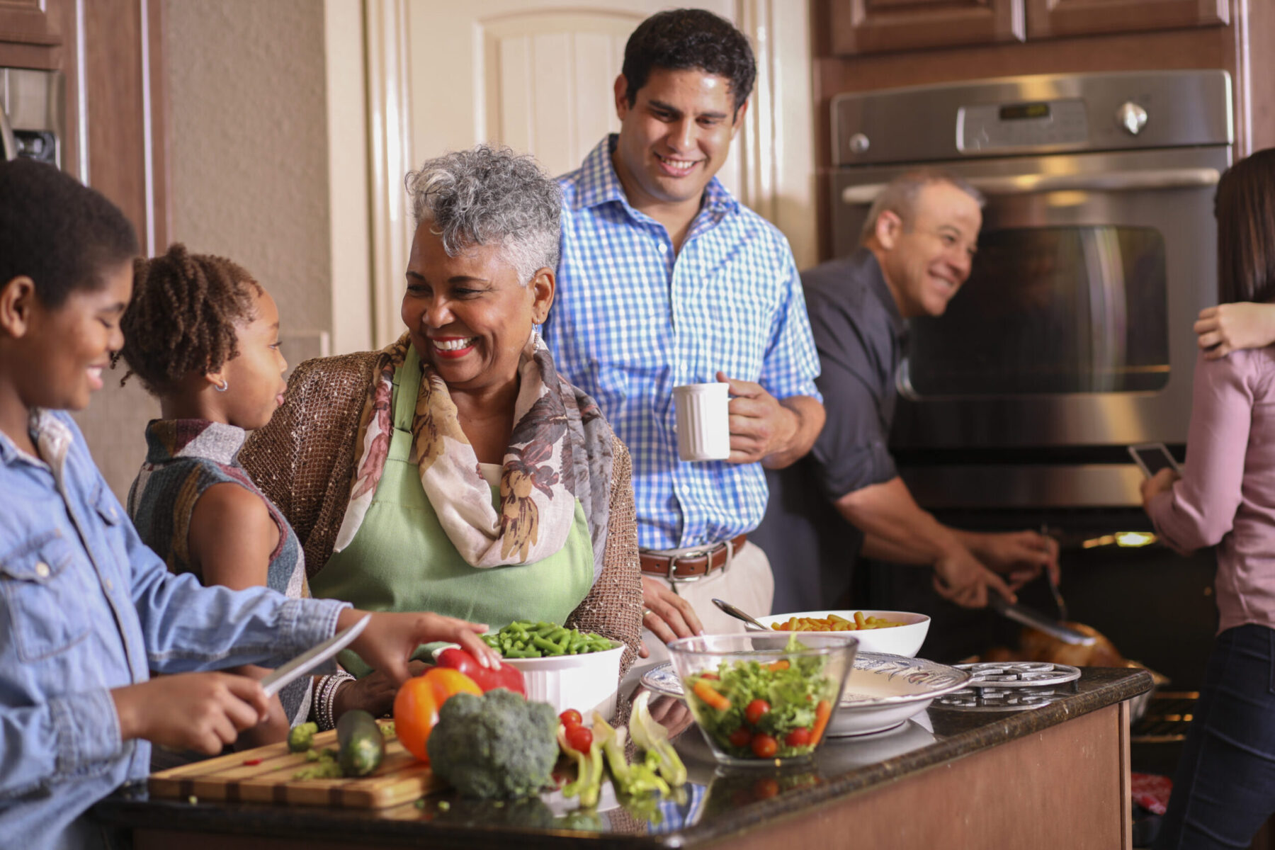 Diverse smiling family in home kitchen cooking Thanksgiving dinner.